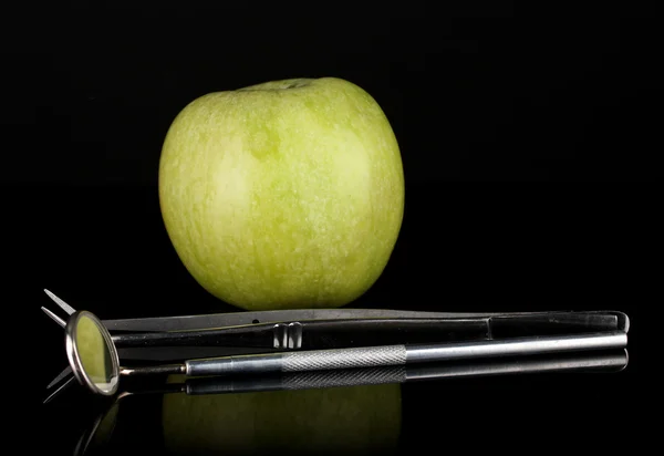 Groene appel en tandheelkundige instrumenten geïsoleerd op zwart — Stockfoto