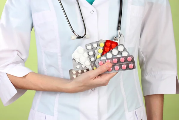 Primo piano della mano medico femminile che tiene pillole, su sfondo a colori — Foto Stock