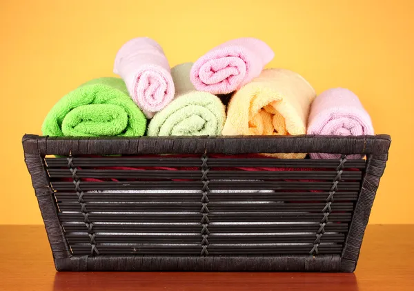 Kleurrijke handdoeken in mand op kleur achtergrond — Stockfoto