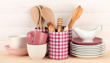 Cups, bowls nd other utensils in metal containers isolated on light background