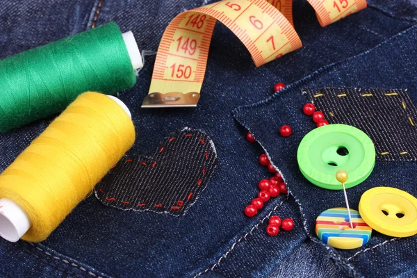 Heart-shaped patch on jeans with threads and buttons closeup — Stock Photo, Image