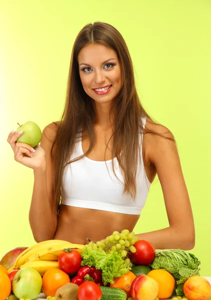 Vacker ung kvinna med frukt och grönsaker, på grön bakgrund — Stockfoto