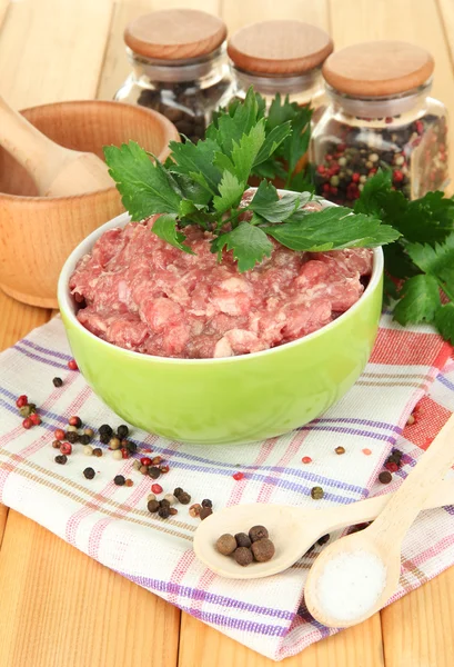 Schüssel mit rohem Hackfleisch mit Gewürzen auf Holztisch — Stockfoto