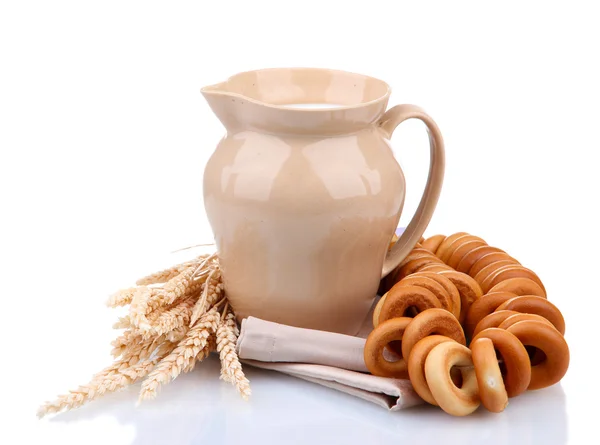 Pot van melk, smakelijke bagels en spikelets, geïsoleerd op wit — Stockfoto