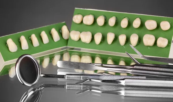 Conjunto de ferramentas dentárias com dentadura sobre fundo cinzento — Fotografia de Stock