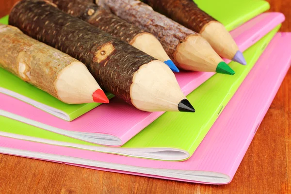 Colorful wooden pencils with exercisebooks on wooden table — Stock Photo, Image