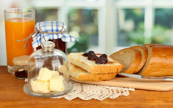 Butter on glass saucer with glass cover and fresh bread, jam on bright background — Stock Photo, Image