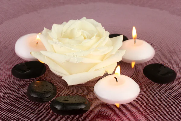 Piedras de spa con flores y velas en agua en el plato —  Fotos de Stock