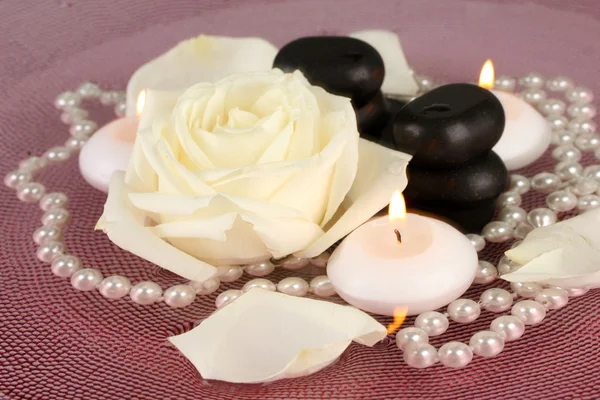 Piedras de spa con flores y velas en agua en el plato — Foto de Stock