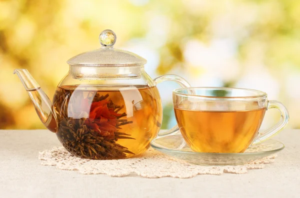 Té verde exótico con flores en tetera de vidrio sobre fondo brillante — Foto de Stock