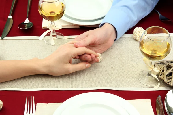 Mãos de par romântico sobre uma mesa de restaurante — Fotografia de Stock