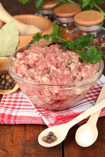 Bowl of raw ground meat with spices on wooden table Stock Image