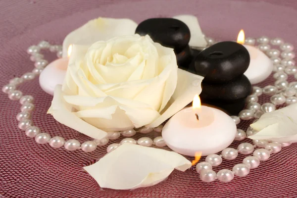 Pietre termali con fiore e candele in acqua sul piatto Foto Stock Royalty Free