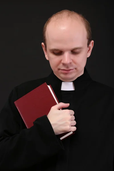 Jeune pasteur avec Bible, isolé sur noir — Photo