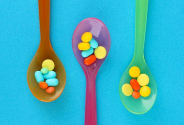 plastik kaşık ile mavi arka plan üzerinde renkli hapları