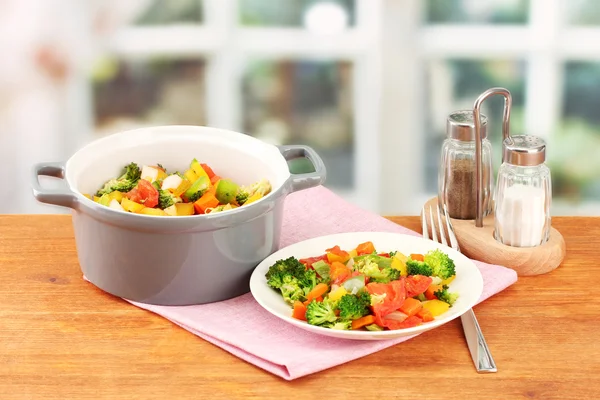 Ragoût de légumes en pot gris sur table en bois sur fond lumineux — Photo