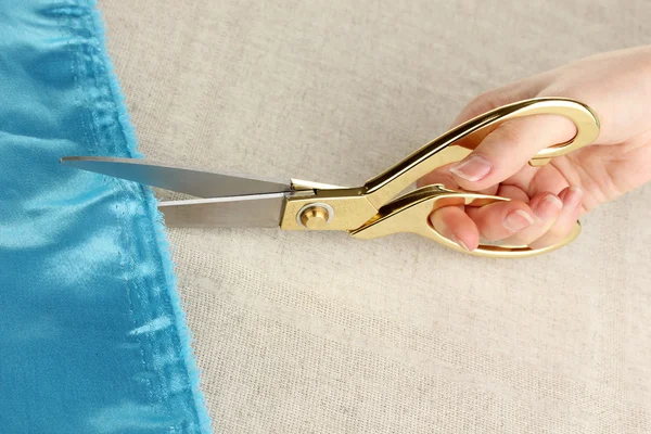 Seamstress corte tecido azul no fundo tecido bege — Fotografia de Stock