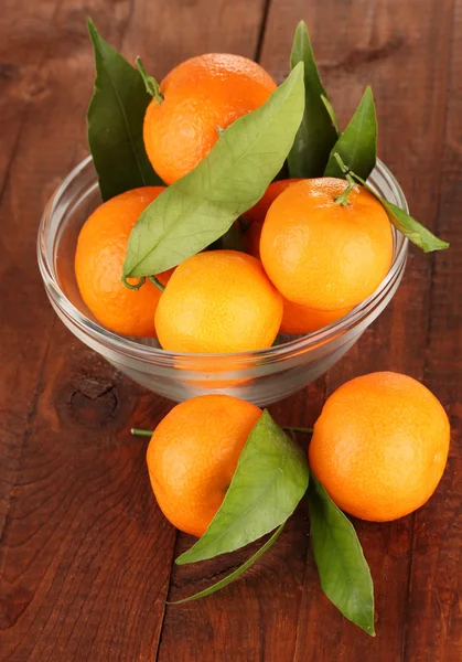 Sweet tangerines with leaves, on wooden background — Stock Photo, Image