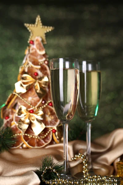 Beautiful christmas tree and glasses of champagne on shine green background — Stock Photo, Image