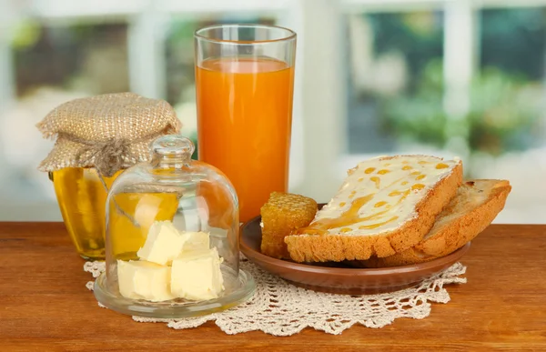 Mantequilla en platillo de vidrio con tapa de vidrio y pan fresco, miel, sobre fondo brillante — Foto de Stock