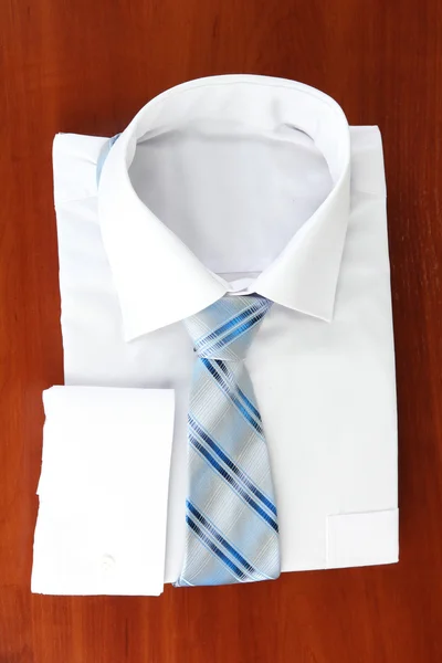 New white man 's shirt with color tie on wooden background — стоковое фото