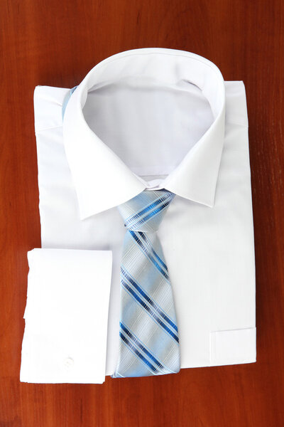 New white man's shirt with color tie on wooden background