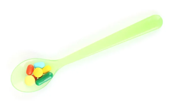 Colher de plástico com pílulas de cor, isolado em branco — Fotografia de Stock