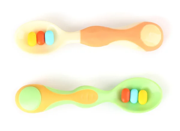 Cucchiai di plastica con pillole di colore, isolati su bianco — Foto Stock