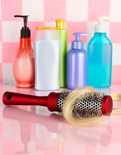 Cepillo de peine con pelo y botellas de cosméticos en el baño — Foto de Stock