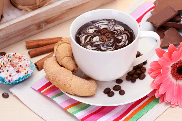 Cup of coffee and gerbera beans, cinnamon sticks on wooden table — Stock Photo, Image