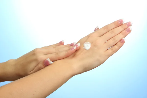 Beautiful woman hands with cream, on blue background — Stock Photo, Image