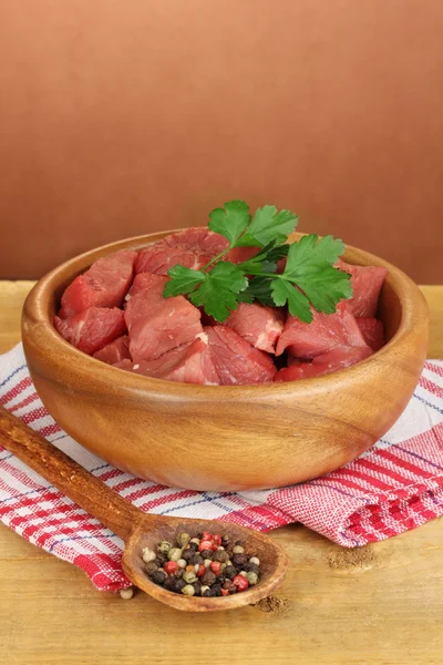 Raw beef meat with herbs and spices on wooden table on brown background — Stock Photo, Image