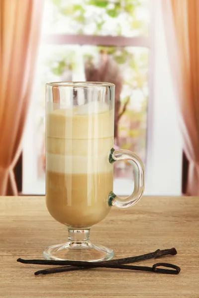 Ароматный кофе латте в стеклянной чашке с ванильными стручками, на столе в кафе — стоковое фото