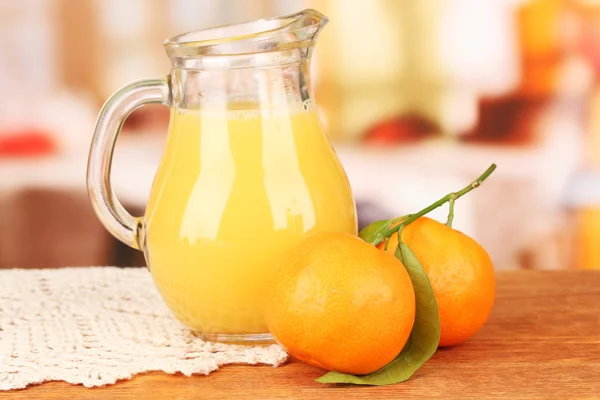 Full jug of orange juice, on wooden table on bright background — Stock Photo, Image