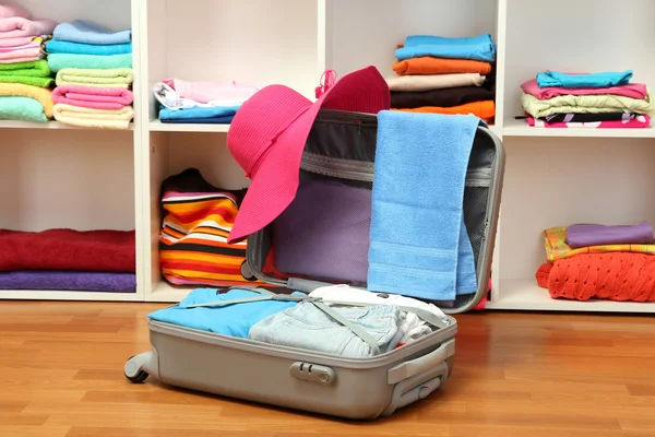 Offener silberner Koffer mit Kleidung im Zimmer — Stockfoto