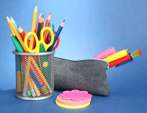 Boîte à crayons avec équipement scolaire sur fond bleu — Photo