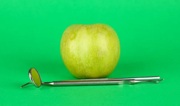 Green apple and dental tools on color background — Stock Photo, Image