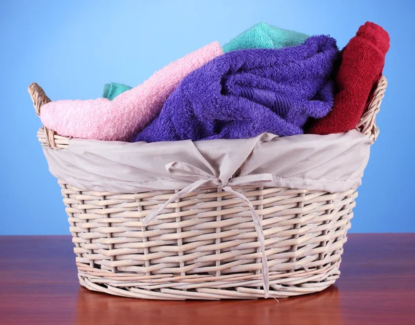 Färgglada handdukar i korg på färgbakgrund — Stockfoto