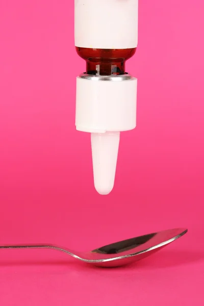 Medical droplet in spoon on pink background — Stock Photo, Image