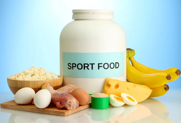 Barattolo di proteine in polvere e cibo con proteine, su sfondo blu — Foto Stock
