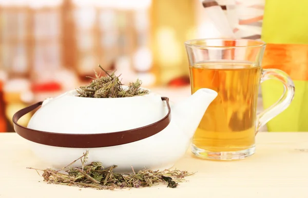 Dried herbs in teapot on wooden table, on bright background. Conceptual photo of herbal tea. — Stock Photo, Image