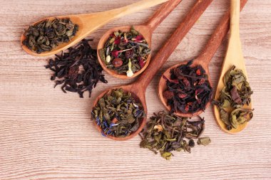 farklı türlerdeki yeşil ve siyah çay kaşığı ahşap masa üstünde kuru