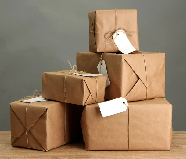 Cajas de paquetes con papel kraft, sobre mesa de madera sobre fondo gris —  Fotos de Stock