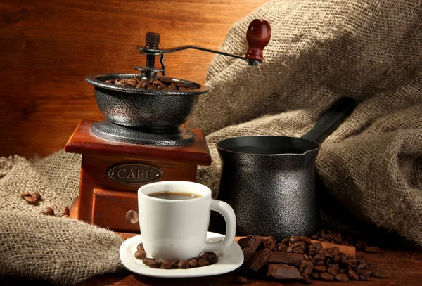 Coffee grinder, turk and cup of coffee on brown wooden background — Stock Photo, Image