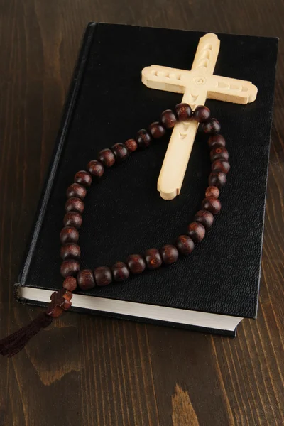Bible, rosary and cross on wooden table close-up — Stock Photo, Image