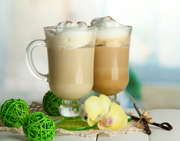 Café con leche aromática en vasos con especias, sobre mesa de madera — Foto de Stock