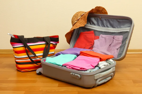 Offener silberner Koffer mit Kleidung im Zimmer — Stockfoto