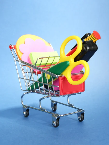 Trolley mit Schulausrüstung auf blauem Hintergrund — Stockfoto