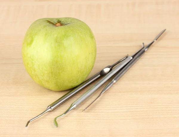 Green apple and dental tools on wooden background — Stock Photo, Image