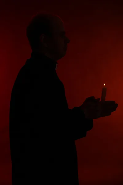 Portrét mladý pastor drží svíčku v ruce, izolované na černém pozadí — Stock fotografie